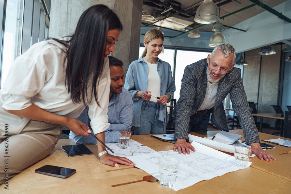 Team of focused professional design engineers working with project documents in modern office 