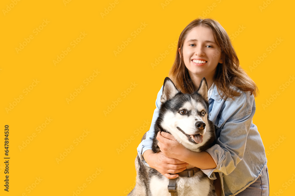 Happy young woman with husky dog on yellow background