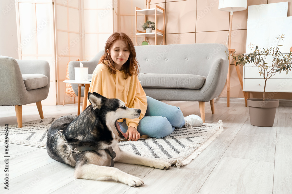 Happy young woman with husky dog at home