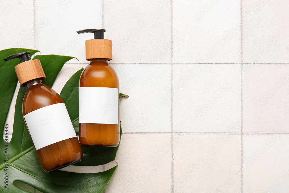 Bottles of shampoo on white tile background