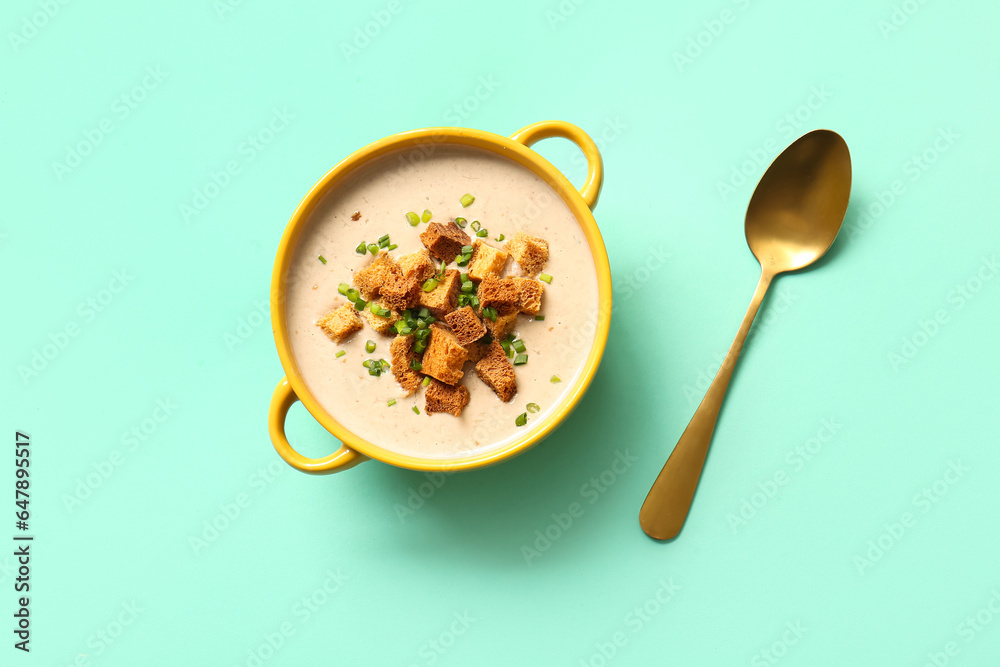 Pot of tasty cream soup with croutons on turquoise background