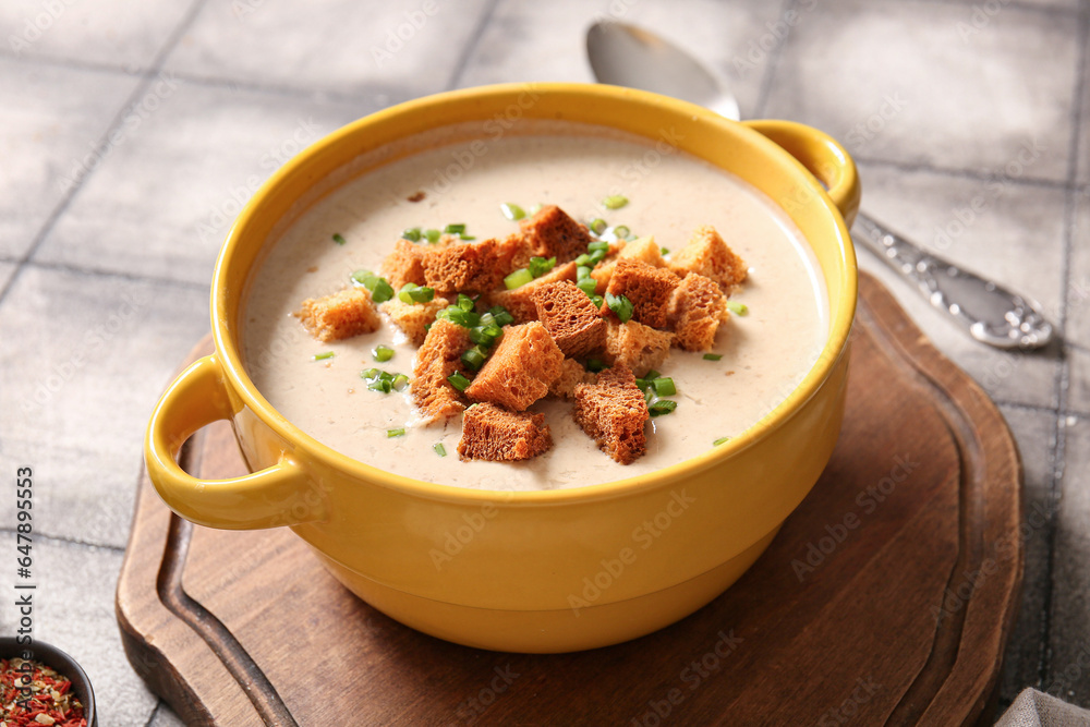 Pot of tasty cream soup with croutons on grey tile background