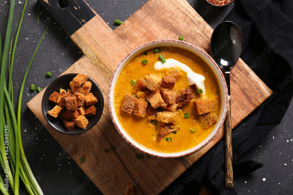 Bowl of tasty cream soup with croutons on black background