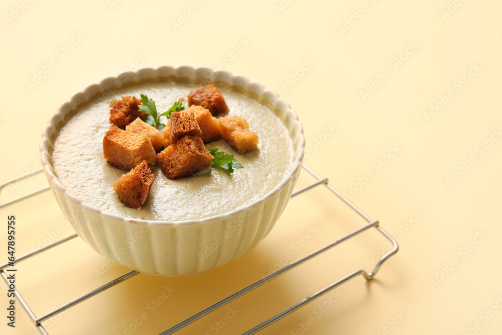 Bowl of tasty cream soup with croutons on yellow background