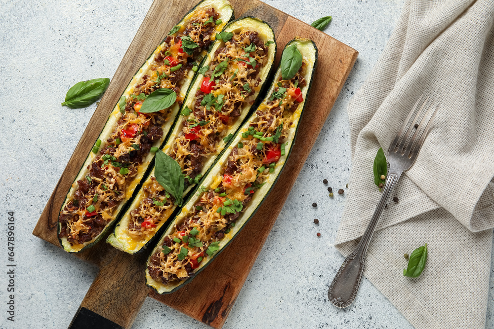 Wooden board with meat stuffed zucchini boats on white background