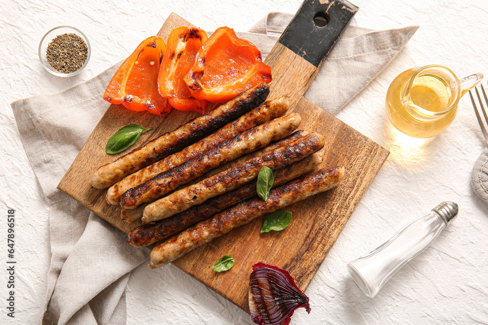 Wooden board of tasty grilled sausages and vegetables on white background