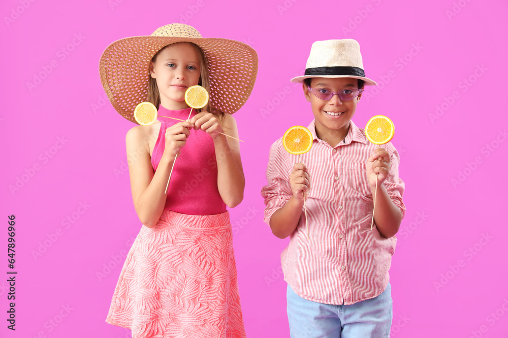 Little children with slices of citruses on sticks against purple background