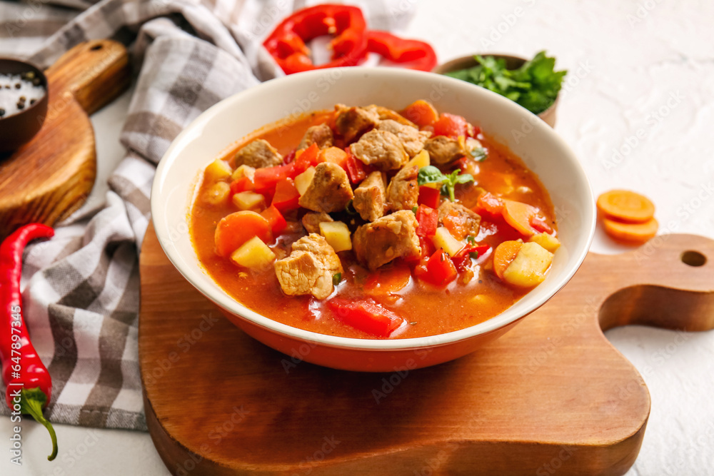 Bowl of tasty beef stew on white background