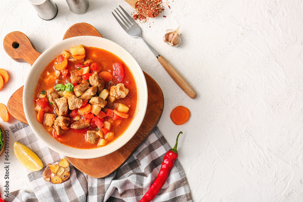 Bowl of tasty beef stew and ingredients on white background