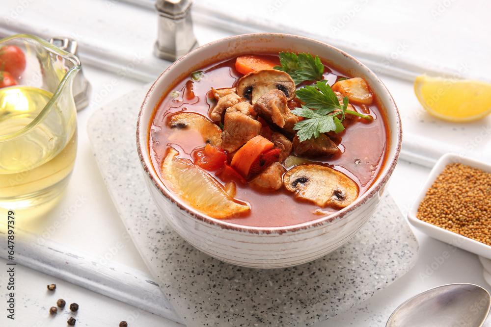 Bowl of tasty beef stew on white wooden background