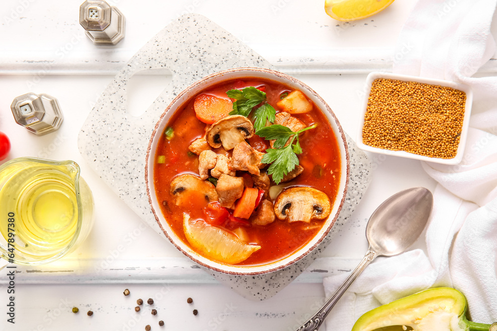 Bowl of tasty beef stew, spices and oil on white wooden background