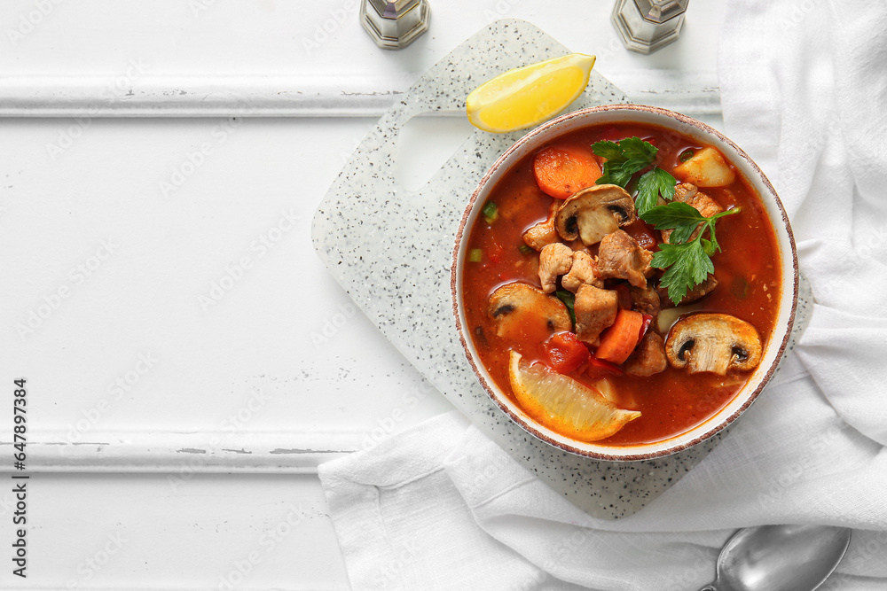 Bowl of tasty beef stew on white wooden background