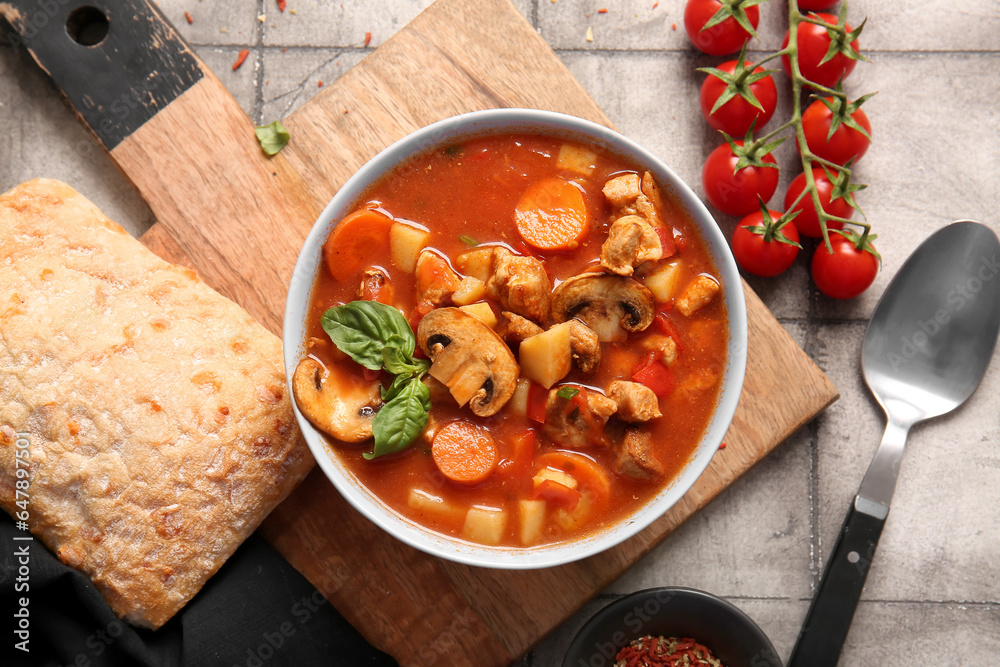 Bowl of tasty beef stew on grey tile background