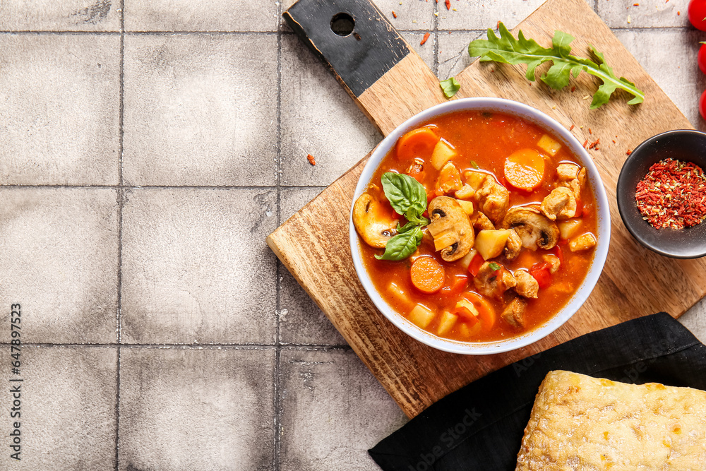 Bowl of tasty beef stew and spices on grey tile background