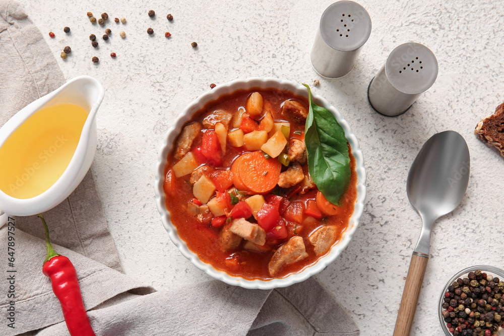 Bowl of tasty beef stew on light background