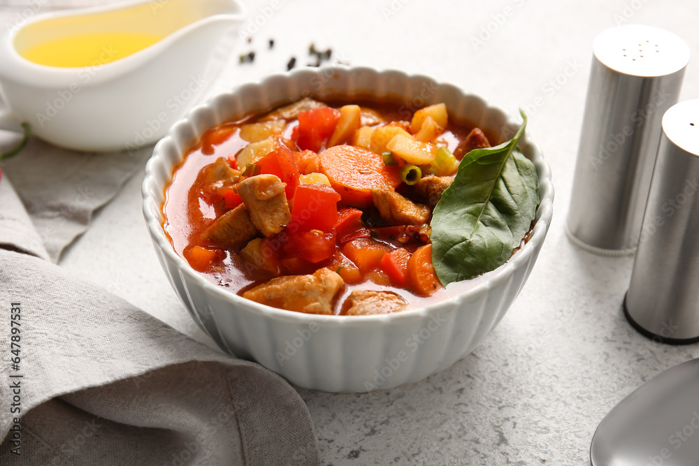 Bowl of tasty beef stew on light background