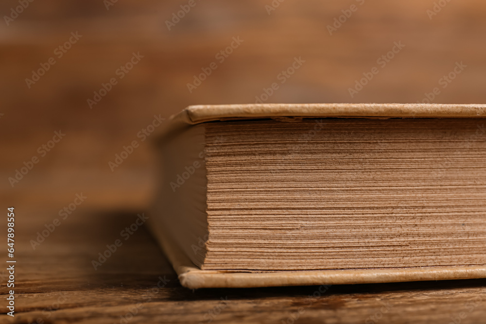 Old hardcover book on wooden background, closeup