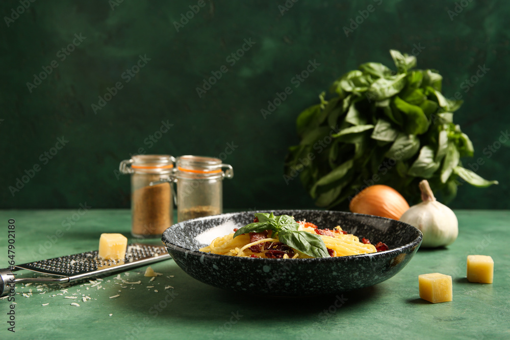 Bowl with tasty pasta carbonara on green background