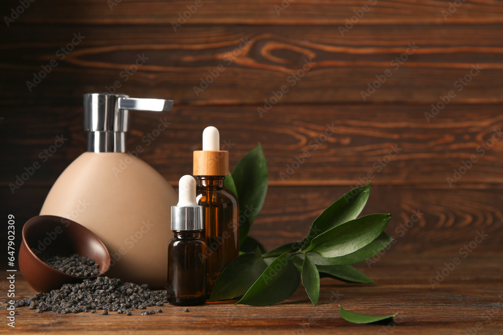 Bottles of essential oil, shampoo and sea salt on wooden background