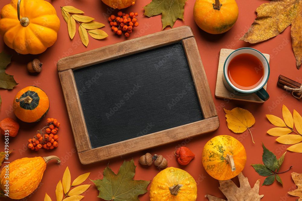 Autumn composition with blank chalkboard, cup of tea, pumpkins and natural forest decor on color bac