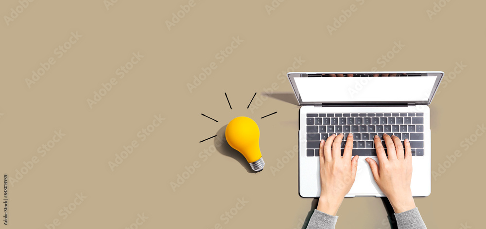 Person using a laptop computer and a light bulb - Flat lay