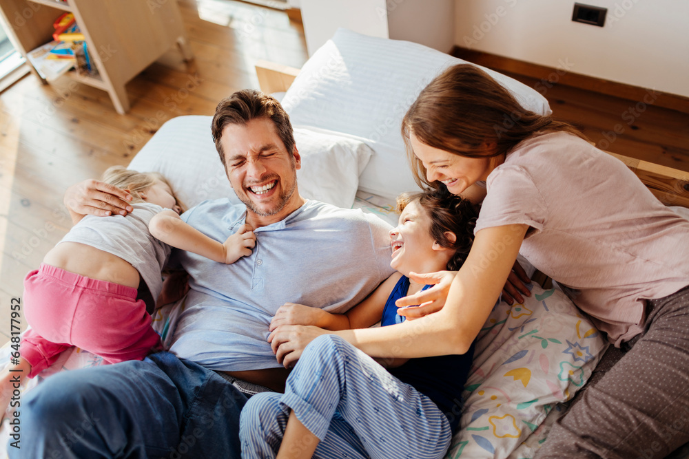 Young caucasian family having fun and playing together in the bedroom in their pyjamas