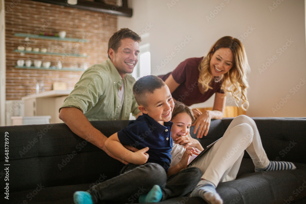 Young caucasian family using a tablet on the couch in the living room