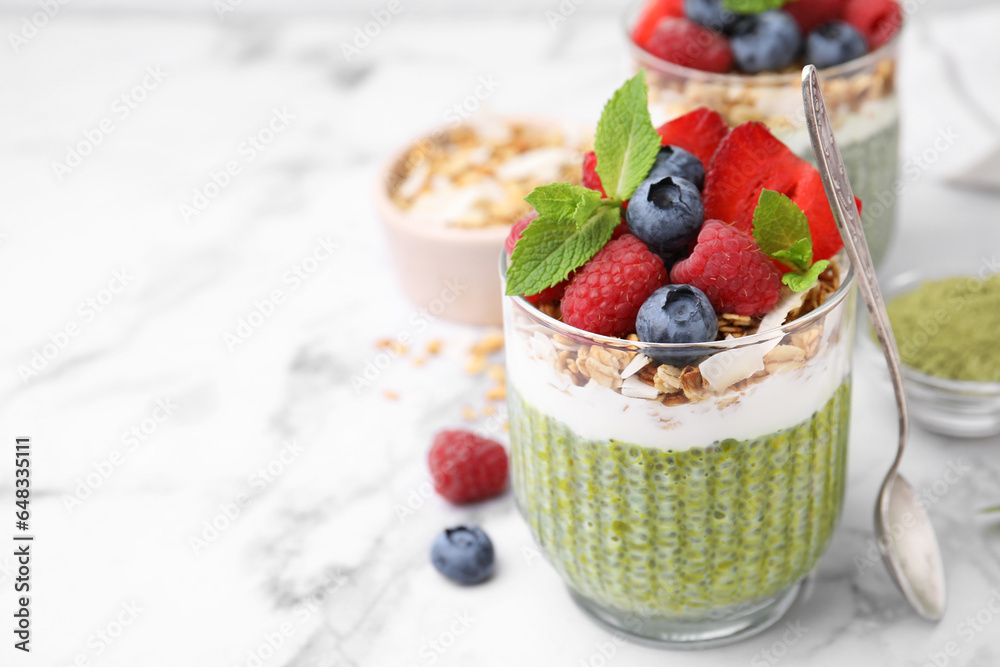 Tasty matcha chia pudding with oatmeal and berries on white marble table, closeup. Space for text. Healthy breakfast