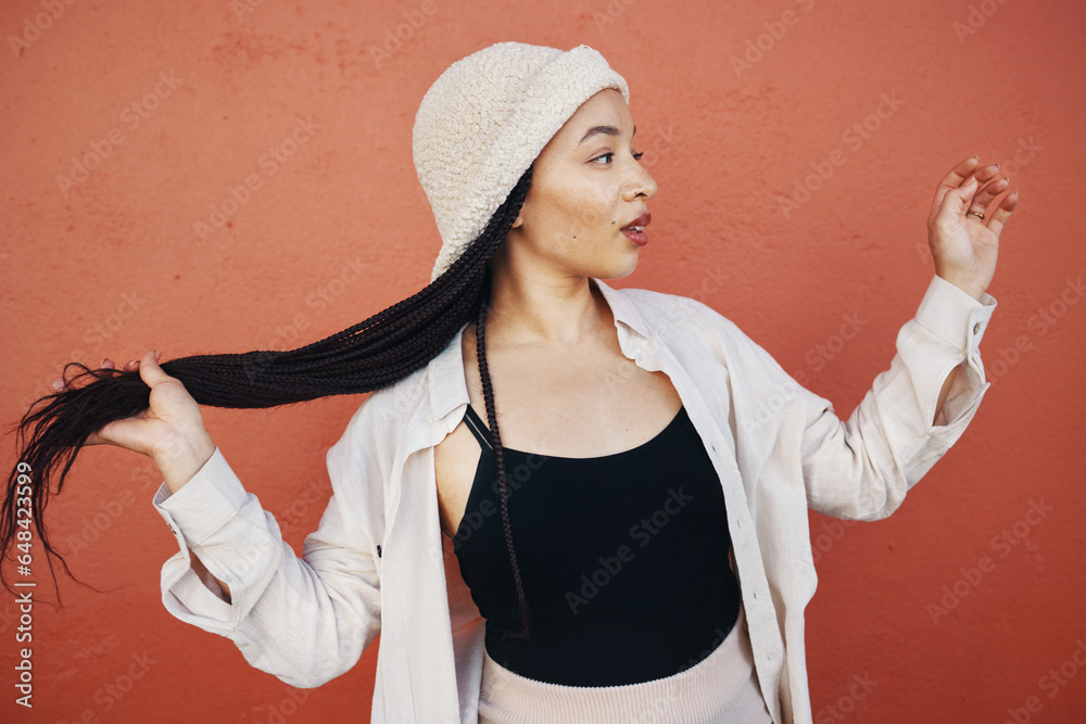 Fashion, hair and African woman in city with trendy outfit, cool clothes and style for glamour. Beauty, makeup and person on orange wall background with confidence, pride and cosmetics in urban town