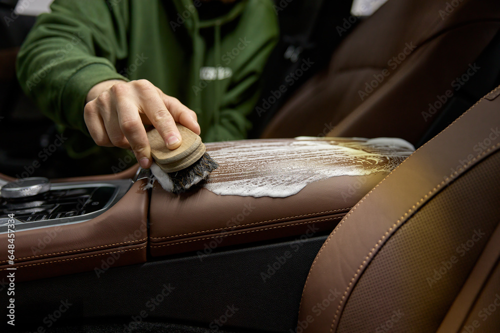 Closeup leather car interior cleaning with foam detergent and brush