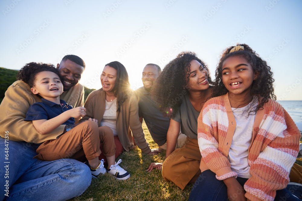 Parents, grandparents and children on grass outdoor laughing together on funny vacation in summer. Interracial family on beach for holiday picnic with smile of men, women and kids for generation love