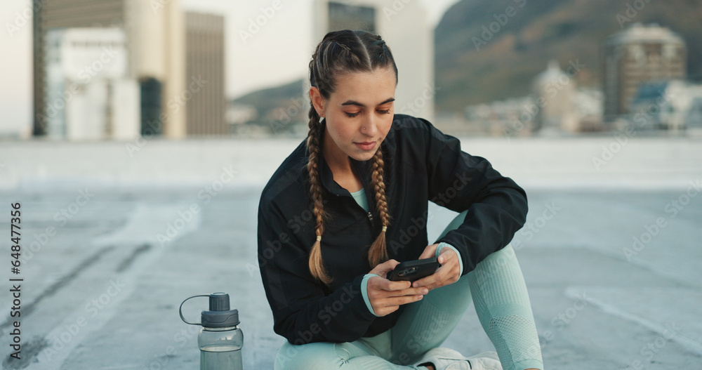 Phone, exercise and woman on social media in city on a rooftop on workout break outdoor. Fitness, communication and girl athlete networking on the internet with smartphone after cardio training