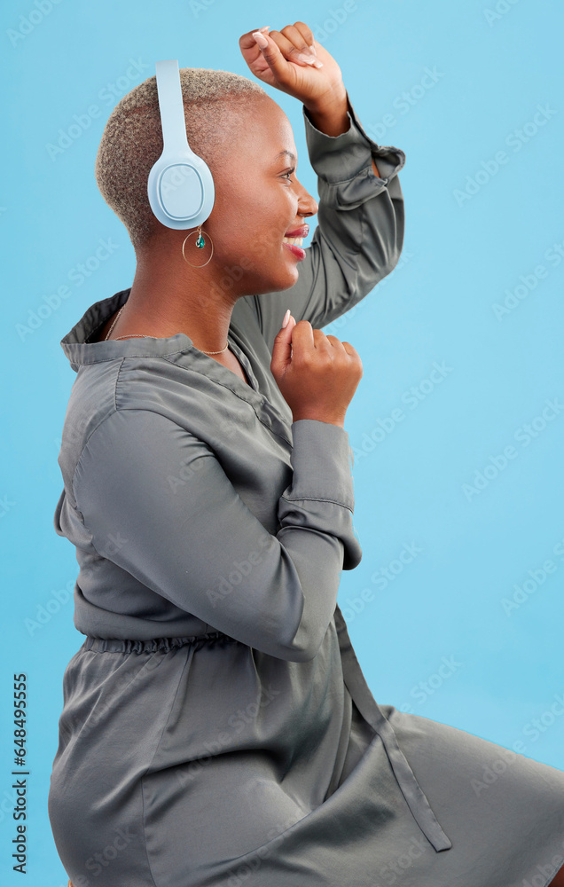 Black woman, headphones and dancing in studio profile, happy and listening by blue background. African dancer girl, smile and streaming subscription for sound, audio tech and hearing for celebration