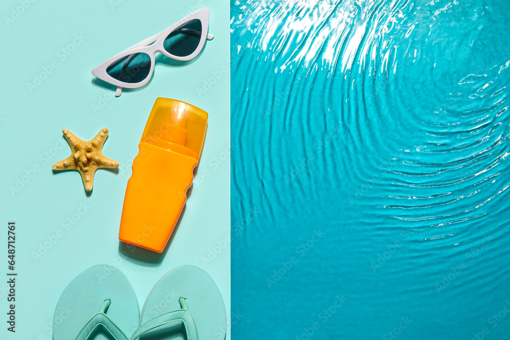 Bottle with sunscreen cream, sunglasses and flip flops on edge of swimming pool