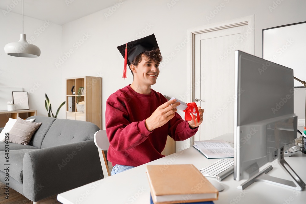 Male graduate student with diploma video chatting at home