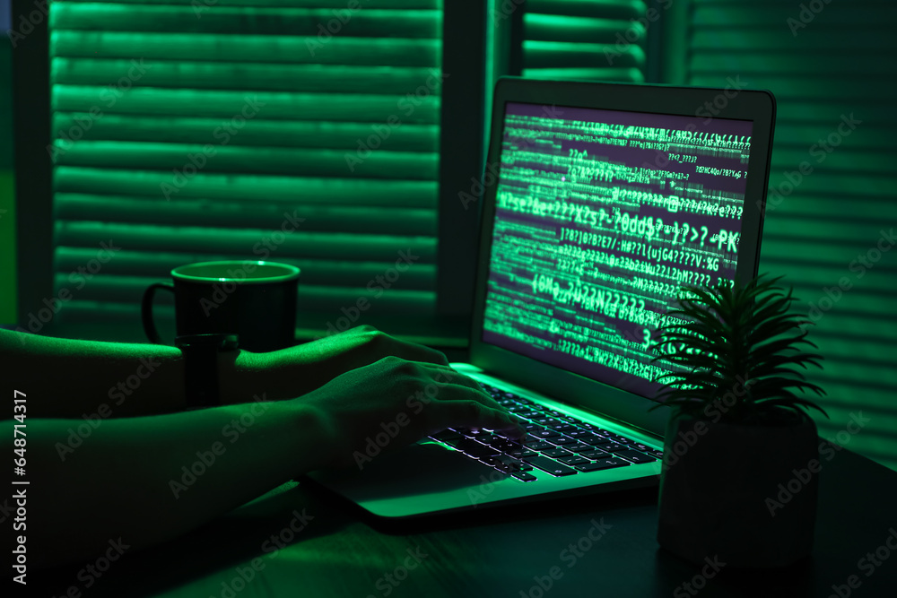 Female programmer typing on laptop keyboard at night in office, closeup