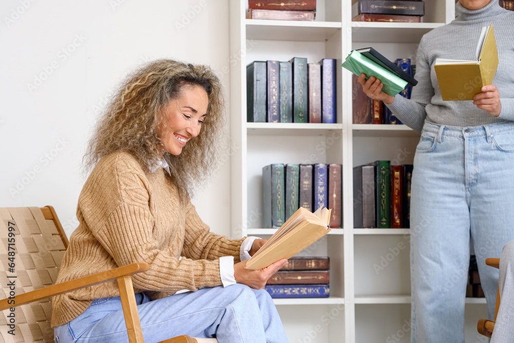 Mature woman reading book at home library