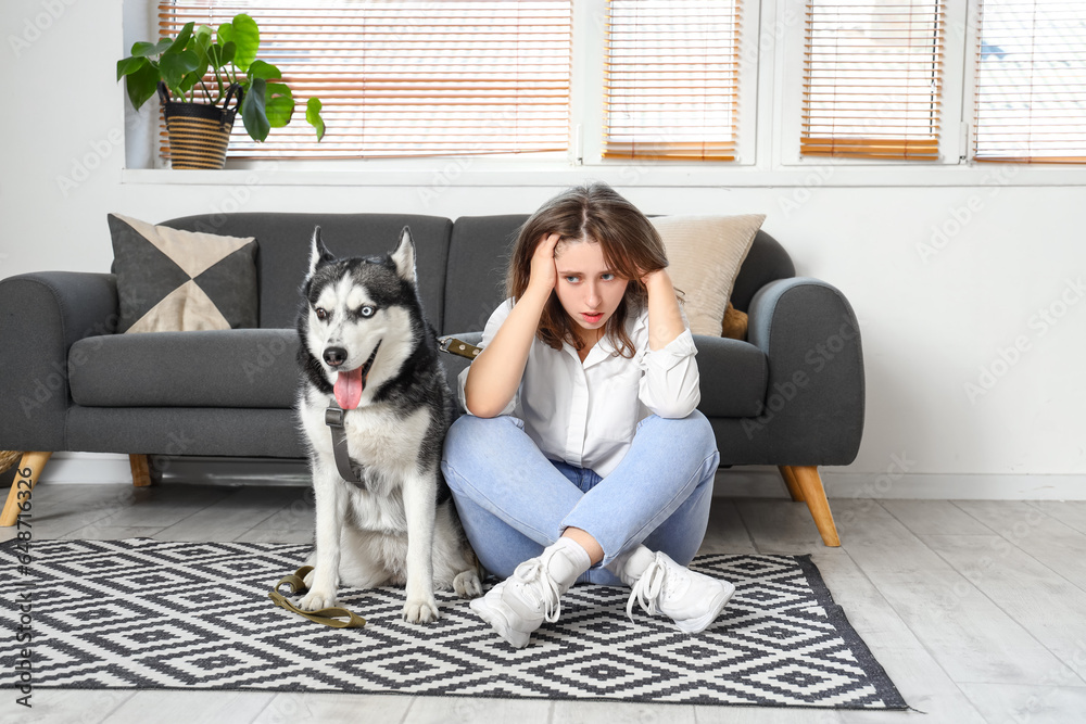 Depressed young woman with husky dog at home