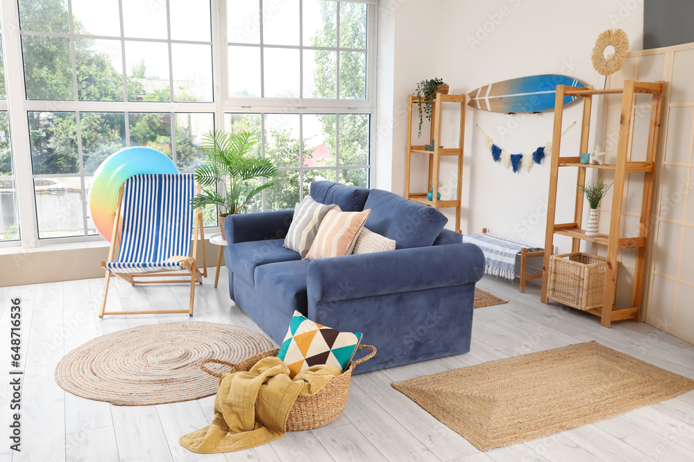 Interior of stylish living room with surfboard and different beach accessories