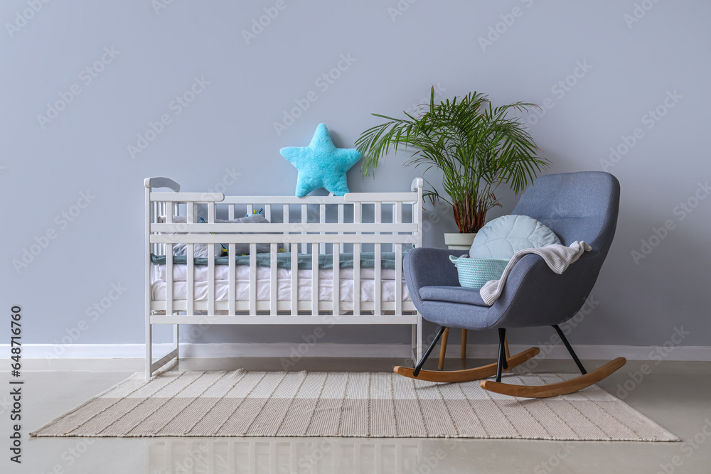 Interior of childrens room with crib and rocking chair near white wall