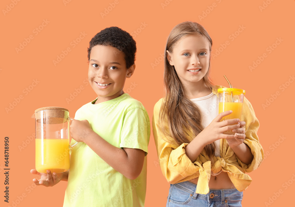 Little children with cup and jug of fresh citrus juice on orange background