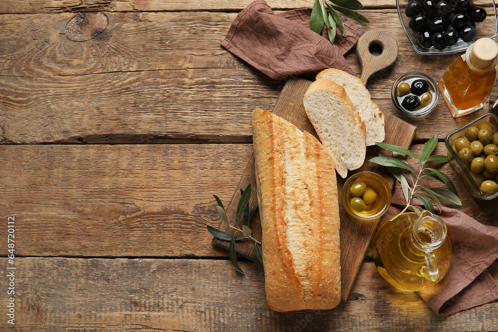 Bowls with olives, oil and bread on wooden background