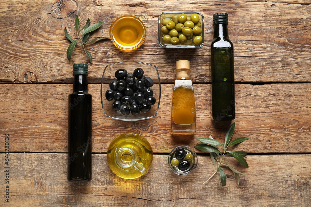 Different glassware of olives and oil on wooden background