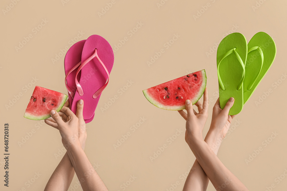 Female hands with slices of ripe watermelon and flip flops on beige background