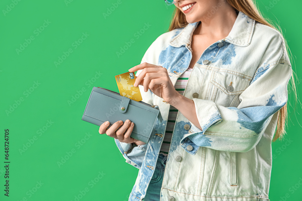 Young woman with credit card and wallet on green background, closeup