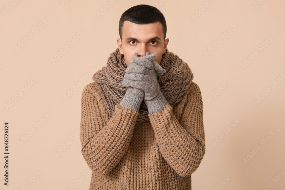 frozen young man in winter clothes on beige background