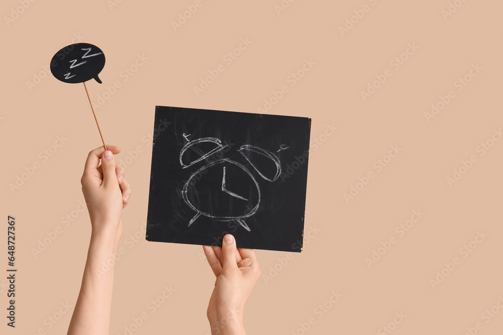 Female hands holding  speech bubble and board with drawing of alarm clock on beige background