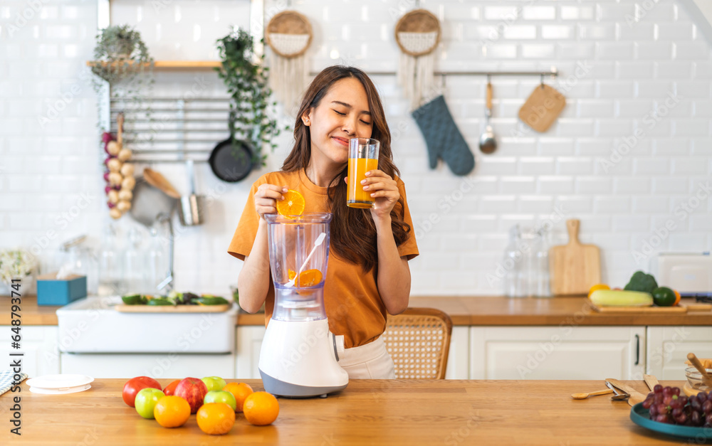 Portrait of beauty healthy asian woman making orange fruit smoothie with blender.girl preparing cooking detox cleanse with fresh orange juice in kitchen at home.health, vitamin c, diet, healthy drink