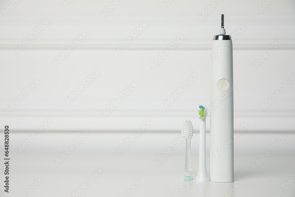 Electric toothbrush and replacement brush heads on white background, space for text