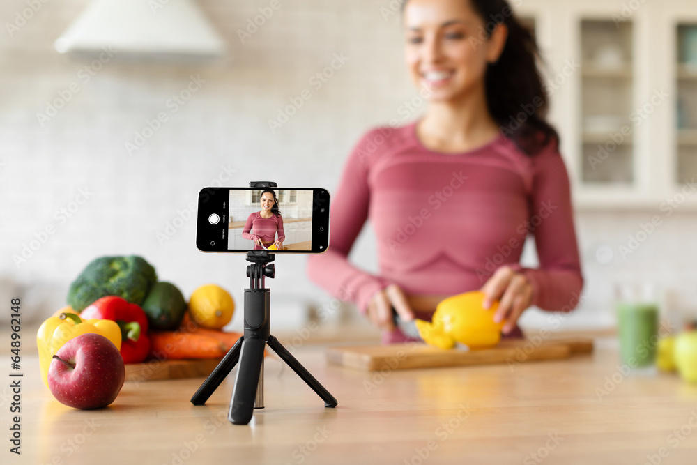 Smartphone With Blogger On Screen While Woman Cooking At Kitchen